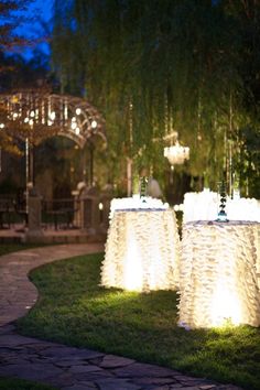 two tables covered in white tablecloths sitting on top of a lush green field