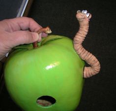 an apple with a worm sticking out of it