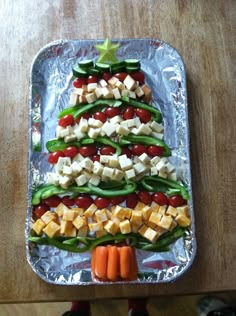 a christmas tree made out of veggies and cheeses on tin foil, sitting on top of a wooden table