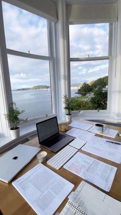 an open laptop computer sitting on top of a wooden desk covered in papers and paperwork