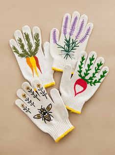 three white gloves with embroidered designs on them, one has a bee and the other has carrots