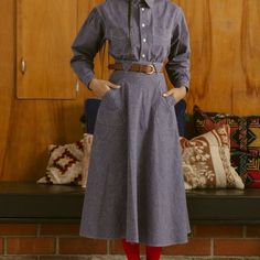 a woman standing in front of a fireplace wearing a blue dress and red tights