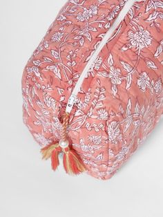 a pink and white floral print bag with tassels