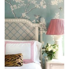 a white bed sitting next to a pink lamp on top of a dresser under a blue wall