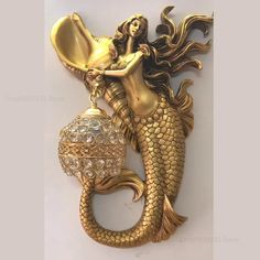 a gold colored mermaid holding a lamp