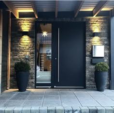 a black door with two planters on each side and lights above the entrance to a house