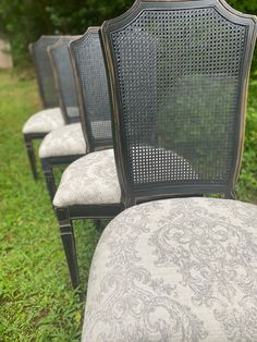 four black chairs sitting on top of a lush green field