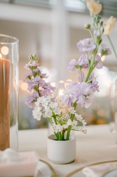 flowers in a vase sitting on a table next to a candle and some candlesticks