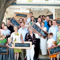 a large group of people holding up signs in front of a house that says welcome to mr and mrs smith