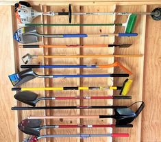 there is a rack that has many different types of tools on it, including brooms and rakes