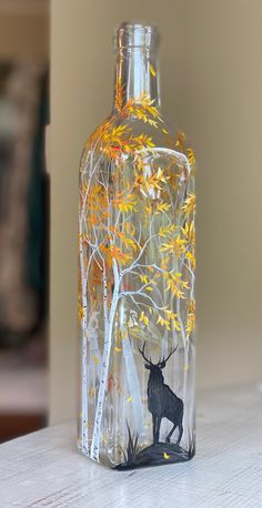 a glass bottle with an image of a deer in the woods on it's side