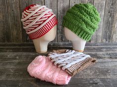 three knitted hats sitting next to each other on top of a wooden table in front of a wood wall