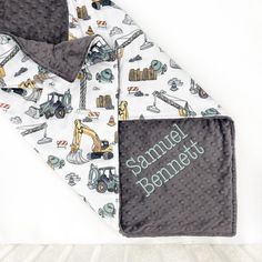 a baby blanket and bib set with construction vehicles on it, sitting on top of a bed