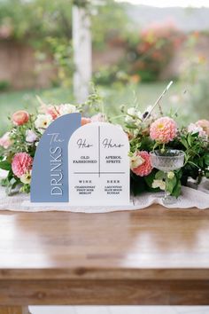 a wooden table topped with flowers and a sign