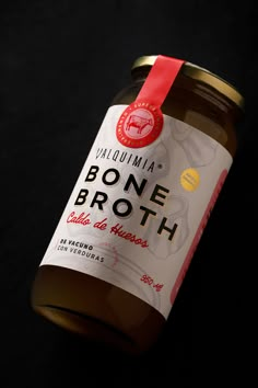 a jar of bone broth sitting on top of a black tablecloth with a red ribbon around it