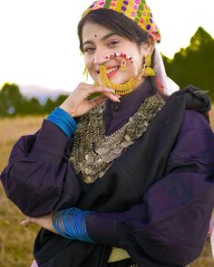 a woman in an elaborately decorated headdress poses for the camera with her nose ring