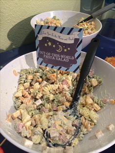 a bowl filled with pasta salad next to a sign