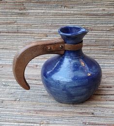 a blue vase sitting on top of a wooden table next to a knife holder with a handle