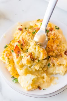 a white plate topped with mashed potatoes covered in gravy and a spoon