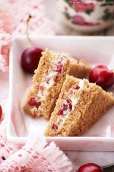 two pieces of cake on a plate with cherries