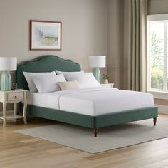 a bed with white sheets and green headboard in a room next to a window