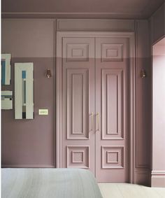 an empty bedroom with pink walls and white bed in the foreground, two mirrors on the wall