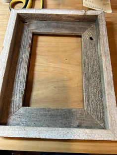 a wooden frame sitting on top of a table next to some scissors and other items