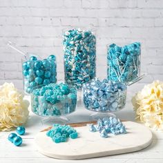 there are many blue and white candies in glass containers next to each other on the table