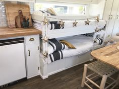 a bunk bed in a kitchen with white cabinets and wood flooring on the side