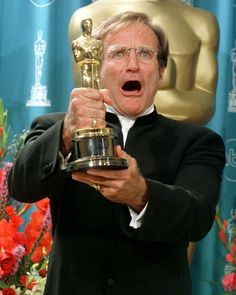 an older man in a tuxedo holds up his oscar statue