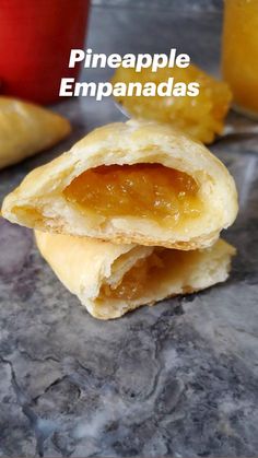 three pastries stacked on top of each other with jelly in the middle and two cups behind them