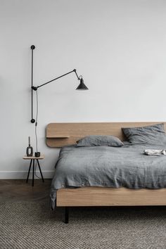 a bed sitting next to a lamp on top of a wooden headboard in a bedroom