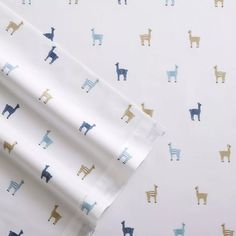 a sheet with llamas on it is laying next to another sheet that has blue and gold llamas on it