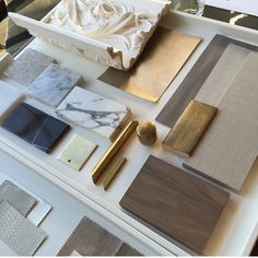 various materials are displayed on a table with white marble and gold accents, such as wood