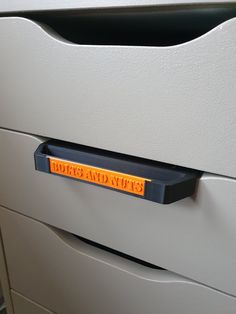 an office file cabinet with a yellow label on the drawer and two drawers behind it