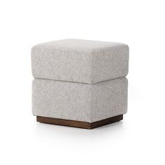 a grey ottoman sitting on top of a white floor