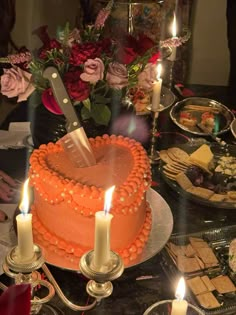 a cake on a table with candles and flowers in the background, surrounded by other food items