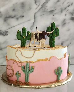 a cake decorated to look like a desert with cactus and cow figurines on top