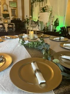 the table is set with gold plates and place settings