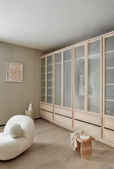 a white chair sitting in front of a book case filled with lots of glass doors