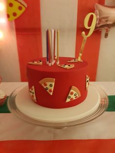 a red cake with pizza slices and candles on it