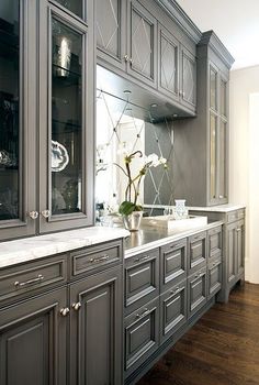 an elegant kitchen with gray cabinets and marble counter tops