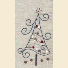 a cross stitch christmas tree is shown on a piece of linen with beads and sequins