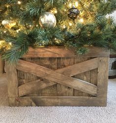 a wooden box with christmas decorations on top of it and a tree in the background