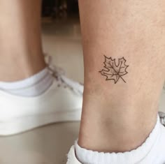 a woman's foot with a small maple leaf tattoo on her left side ankle