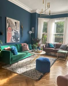 a living room with blue walls and wooden floors is pictured in this image, there are two couches on the hardwood floor