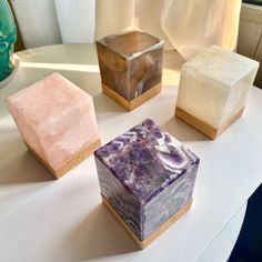 three different types of soaps on a white tablecloth with a vase in the background