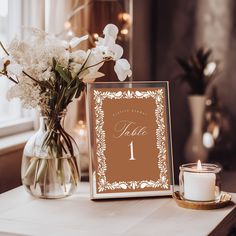 a vase with flowers and a candle on a table next to a sign that says one