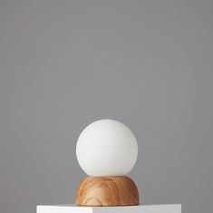 an egg is sitting on top of a white table with a wooden base and light bulb