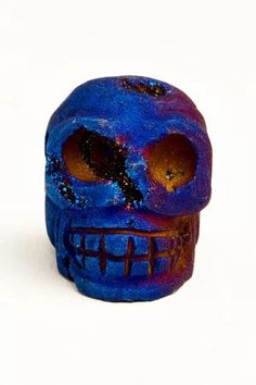 a blue skull with orange eyes on a white surface, it appears to be made out of clay